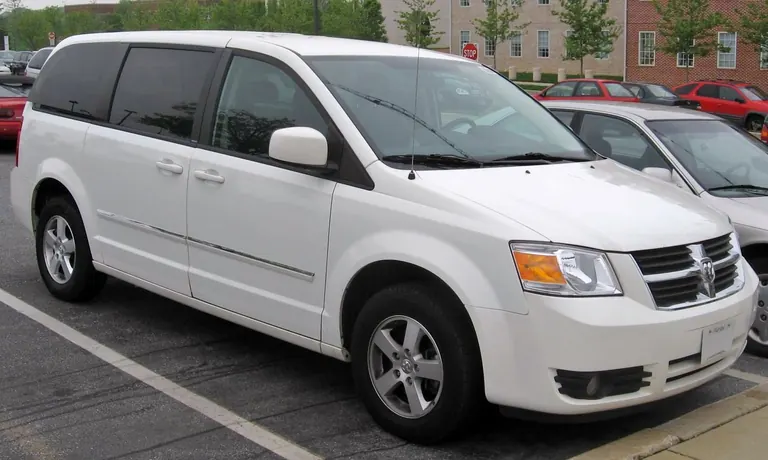 Белый Dodge Grand Caravan пятого поколения на городской парковке