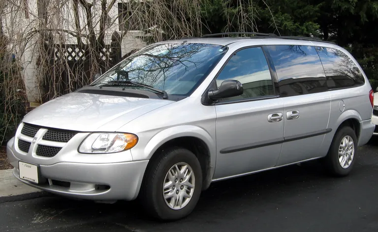 Серебристый Dodge Grand Caravan четвёртого поколения возле жилого дома