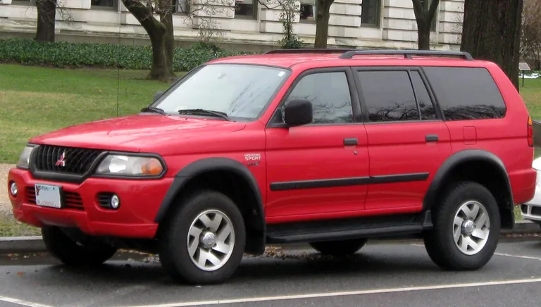 Красный Mitsubishi Montero Sport первого поколения на городской улице